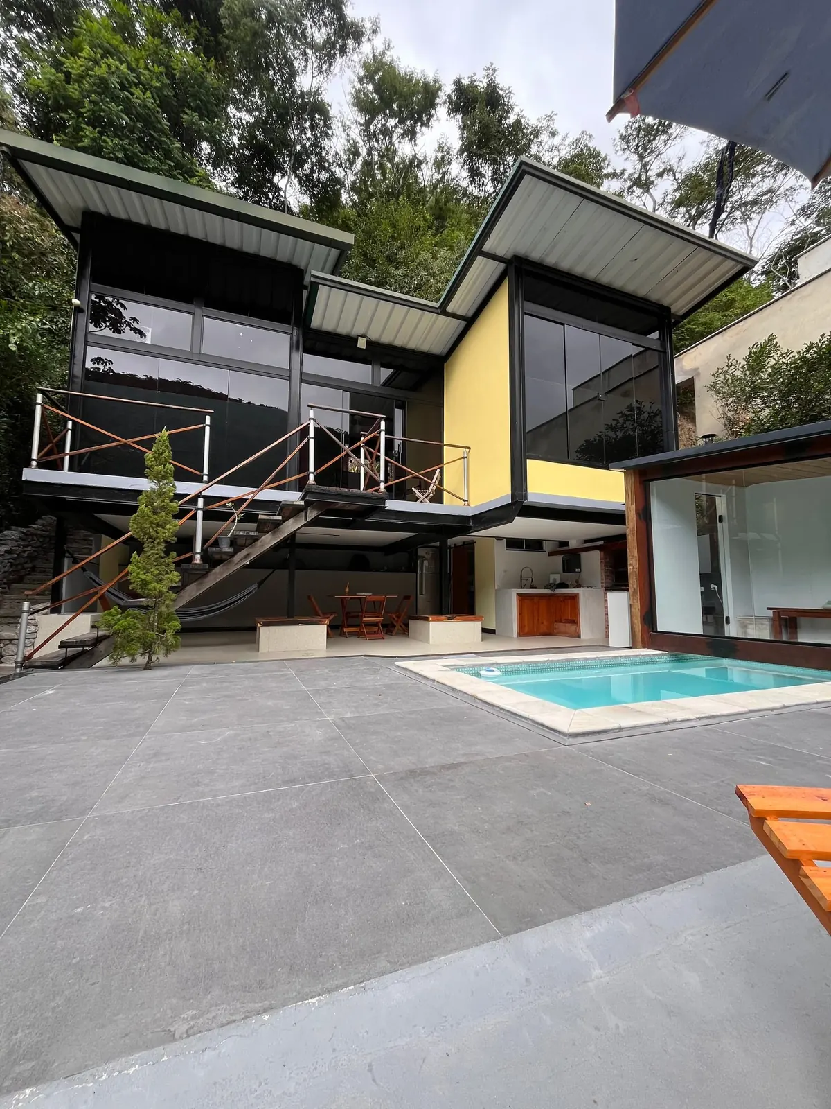 A casa, de vidro e madeira, aberta para a piscina